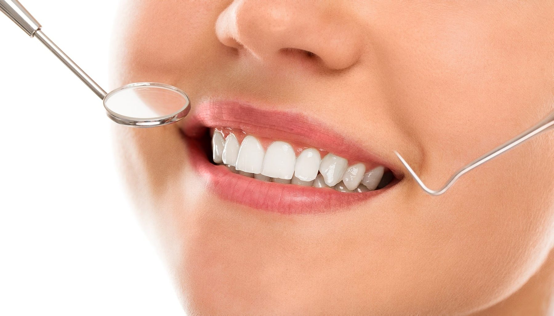 A bright, healthy smile being checked with a dental mirror